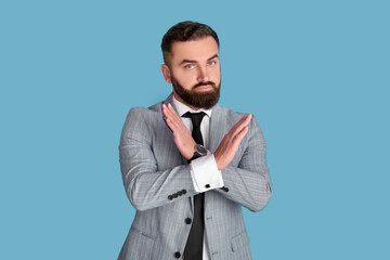 Expressing rejection. Serious bearded entrepreneur in formalwear showing STOP gesture on blue...