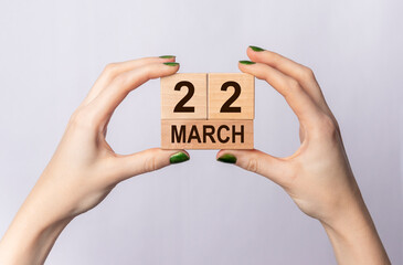 22 March inscription on wooden cubes in female hands