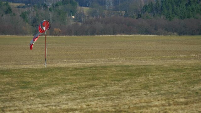 Worn out windsock on abandoned sport airport.  The wind is blowing lazy and windsock is turning and moving. Weather forecast.
