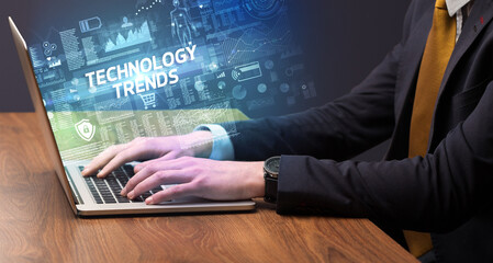 Businessman working on laptop with TECHNOLOGY TRENDS inscription, cyber technology concept