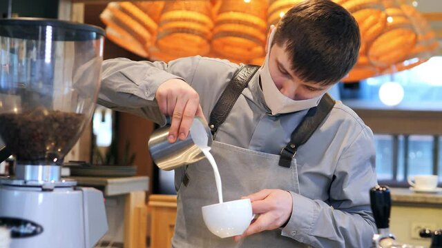 Hand of barista making latte or cappuccino coffee pouring milk making latte art