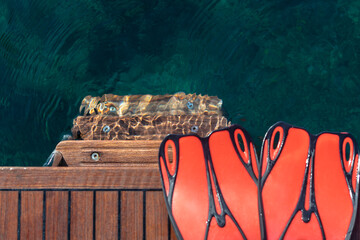 Red swimming flippers on wooden stern of yacht. Selective focus © 22Imagesstudio