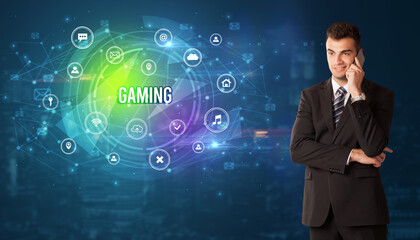 Businessman thinking in front of technology related icons and GAMING inscription, modern technology concept