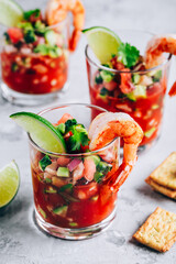Refreshing Mexican Shrimp Cocktail with lime in glass on gray stone background