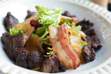 Chicken liver and bacon salad close-up on a white plate