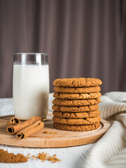 Cookies, milk and cinnamon on a cutting board. White wood background