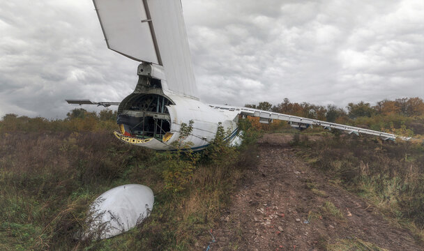 An abandoned old Soviet cargo plane lying on the ground in cloudy weather. Broken tail of an airplane