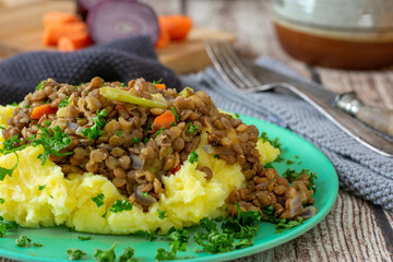 Vegetarian dish with lentil stew and mashed potatoes on a bamboo plate