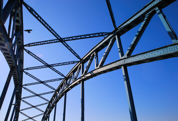 Low angle view on isolated symmetrical industrial steel bridge deck against blue sky with cross struts and metal beams (focus on right girders in front)