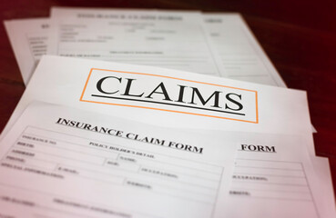 In selective focus of CLAIMS letter on white paper,at the middle of blurred Insurance Claim form,