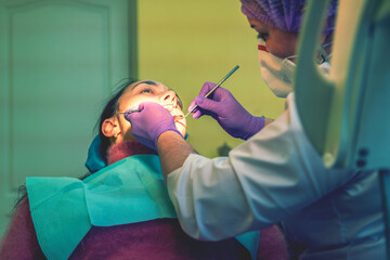 Male dentists examining and working on young female patient.Dentist's office. Real woman in a chair at the dentist. toned