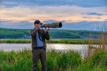 Wildlife photographer on big lake background in summer time