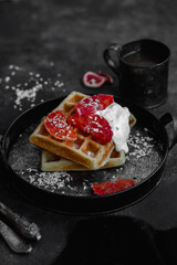 Belgian waffles with a bloody orange on a dark plate. Dark photo