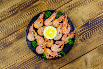 Red boiled prawns with lemon and parsley on wooden table. Top view