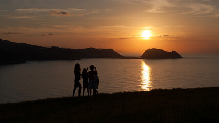 Silhouette of a family at sunset on the coast of Zarautz in the Basque country with the Getaria mouse in the background