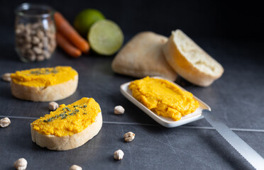 Homemade hummus chickpea spread made of chickpea, carrots, lemon and coriander. Spread over a toast, made of organic ingredients. Refreshing vegan breakfast.