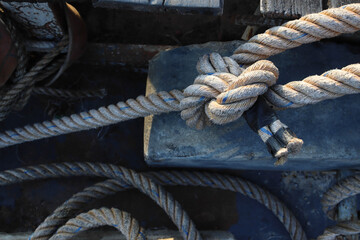 Fototapeta na wymiar Nylon ship ropes tied to knot on cement flooring at port closeup.