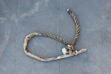 Nylon ship ropes tied to knot on cement flooring at port closeup.