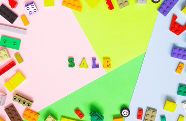 The word "SALE" is made of colored wooden letters on a multi-colored background, a frame in the form of blocks of a children's constructor. Seasonal sale, retail, shopping concept. Black Friday sale.