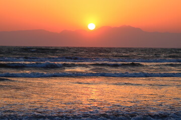 Obraz premium 海岸線から臨む山あいに沈む夕日