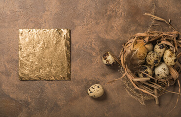 quail eggs in a nest and laid out around it border ,place for text on brown rustic background top view close up