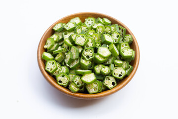 Fresh okra slices in wooden bowl isolated on white
