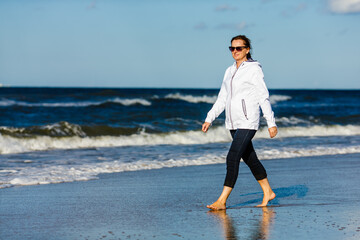 Fototapeta na wymiar Middle-aged woman walking on beach 