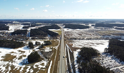 Top view of asphalt highway road among snow fields in winter