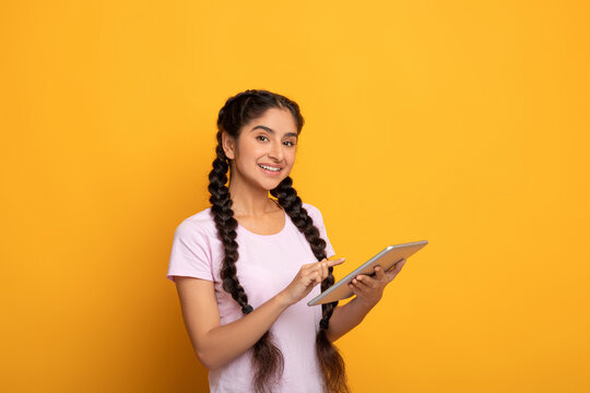 Confident young indian lady holding and using tablet