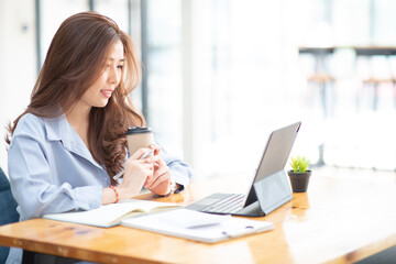 Portrait of Asian Young Female working financial report with tablet at home office.