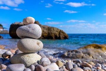 Fototapeta na wymiar Man-built pyramid of four stones of sea pebbles at a seaside resort