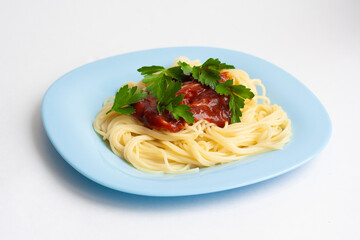 Spaghetti pasta with tomato sauce and herbs in a blue plate on a white background