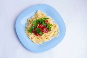 Spaghetti pasta with tomato sauce and herbs in a blue plate on a white background, top view