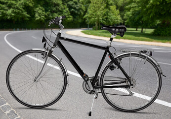 Fototapeta na wymiar Black road bike standing on road from public park
