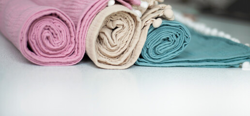 Obraz na płótnie Canvas Multicolored rolls of towels in soft pastel colors. Home textiles made from organic cotton. Textile border. Copy space for text.