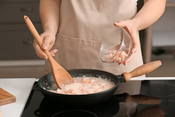 Woman cooking risotto in kitchen