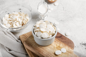 Bowls with chocolate drops on light background