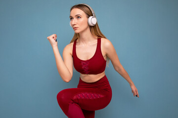 A young woman in a tracksuit and headphones runs on a blue background