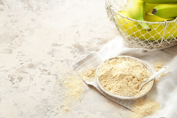 Plate with banana flour on light background