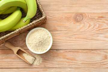Bowl and scoop with banana flour on wooden background
