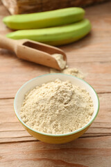 Bowl with banana flour on wooden background