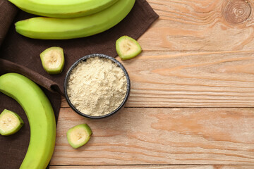 Bowl with banana flour on wooden background