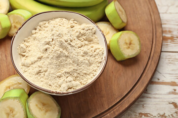 Bowl with banana flour on wooden background