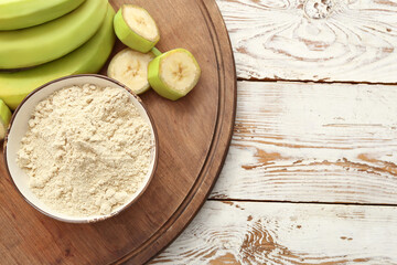 Bowl with banana flour on wooden background