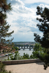 A beautiful view of Prague and Moldau river with bridges through trees of Stalin lookout, Czech Republic