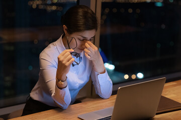 Close up exhausted Indian businesswoman taking off glasses, massaging nose bridge, suffering from...