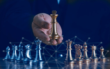 Hand of businessman holding the golden king chess to fighting silver king chess to play successfully in the competition with technolog network background. Management or leadership strategy concept.