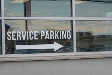 White letters with a white arrow on a window pointing to service parking area