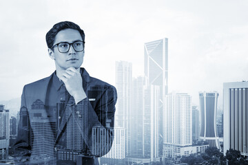 Young handsome businessman in suit and glasses dreaming about new career opportunities after MBA graduation. Kuala Lumpur on background. Double exposure.