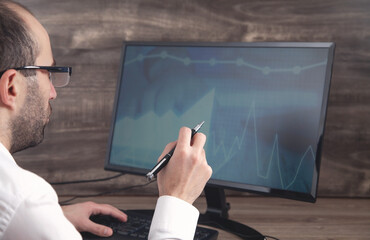 Businessman working with analytics sitting at the working place with computer. Graphs and charts on computer screen. Business. Finance. Accounting